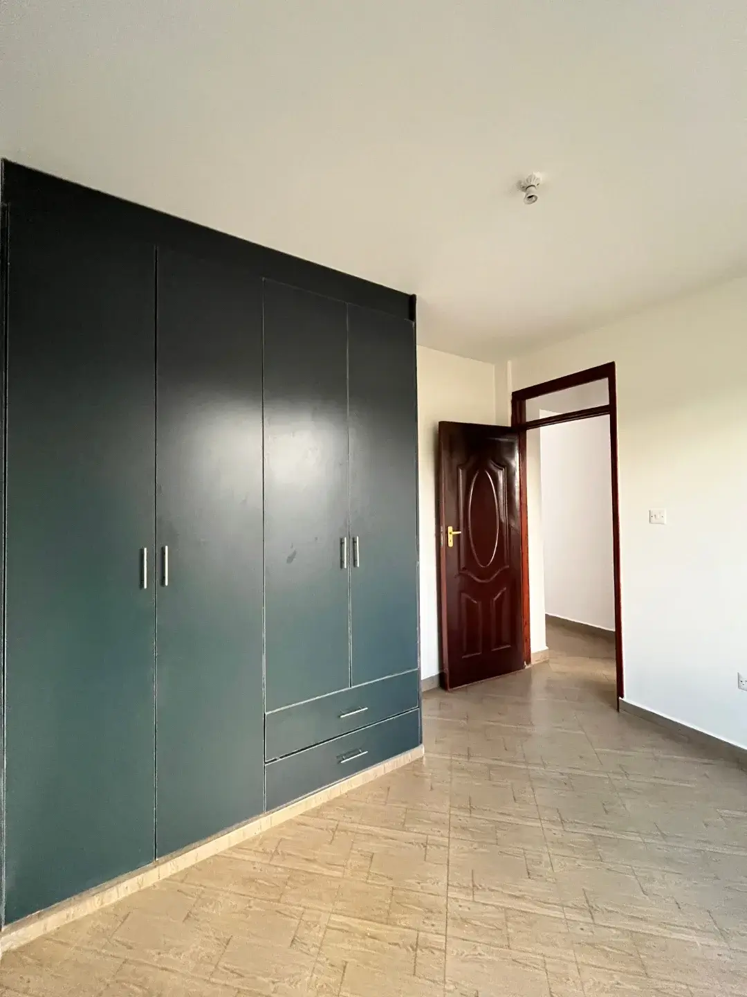 Spacious bedroom with large built-in wardrobe and wooden door