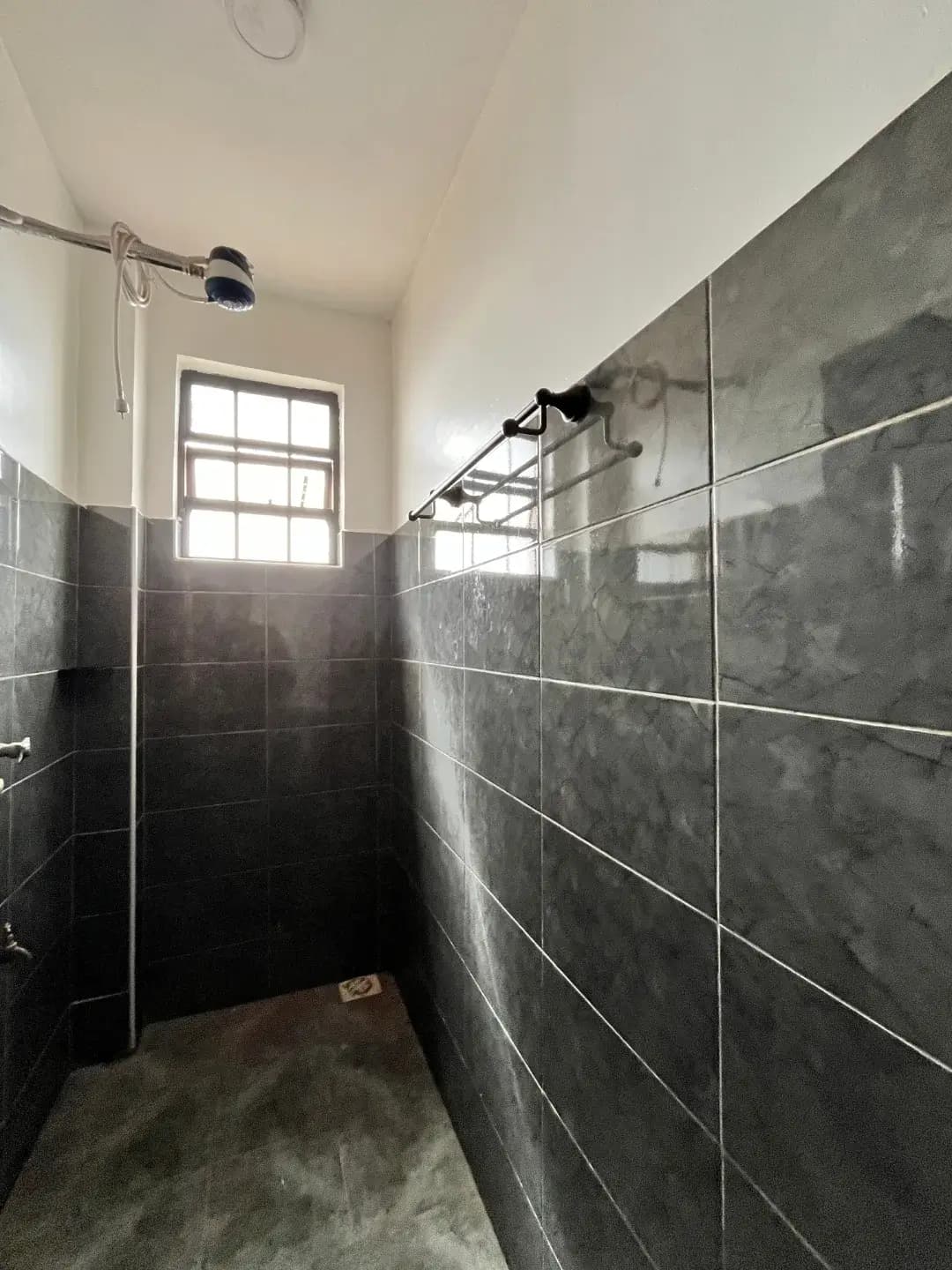 Bathroom with dark tile walls and overhead shower fixture