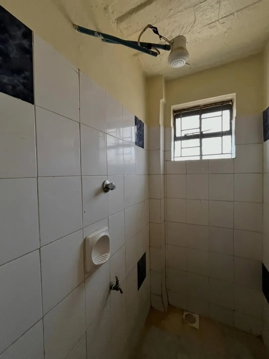 Compact bathroom with white tile shower enclosure and window