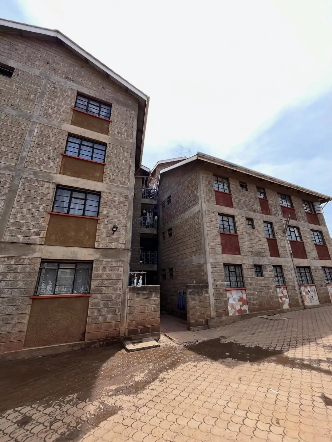 Multi-story brick apartment buildings with paved compound entrance