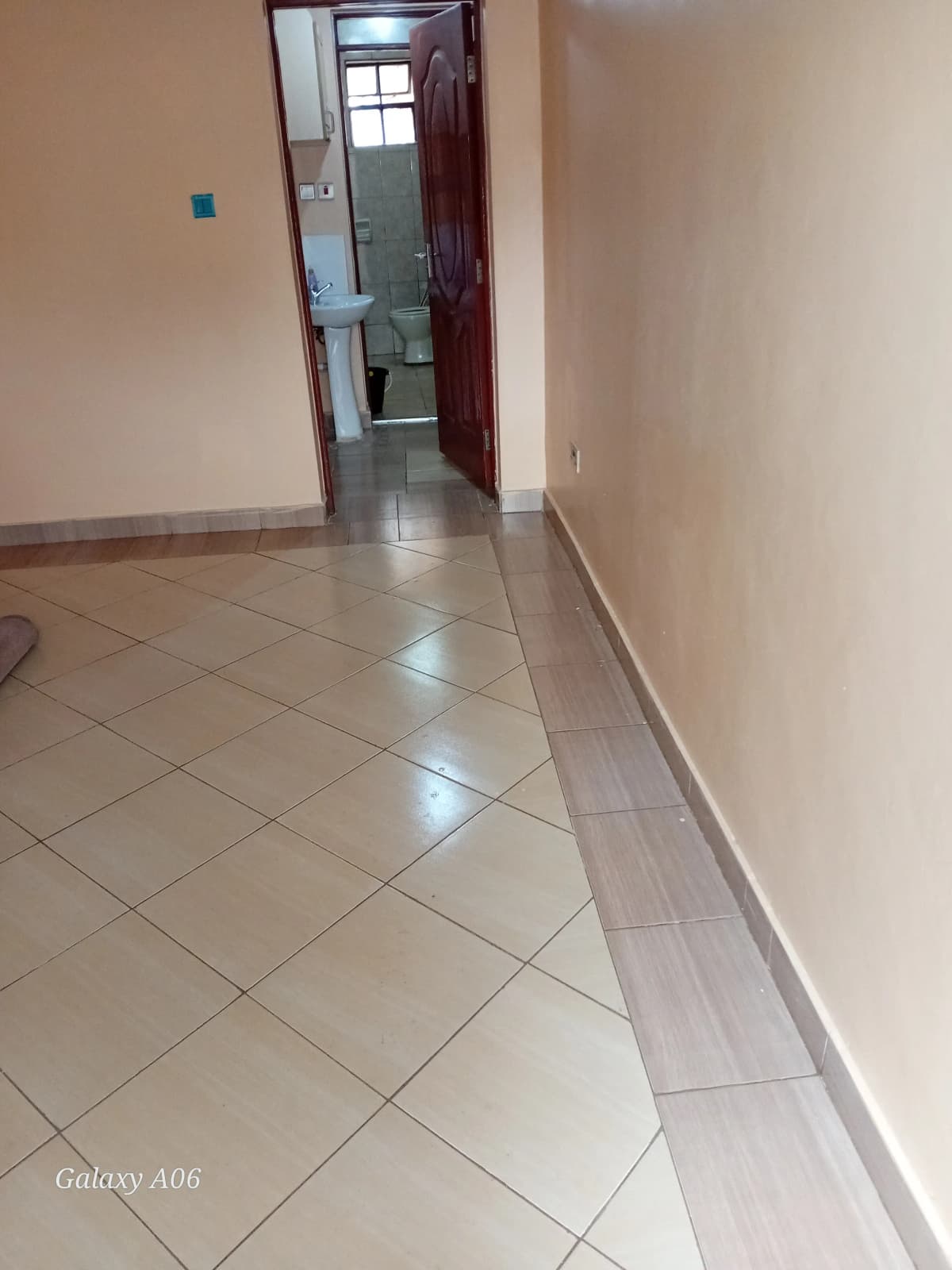 Narrow hallway with tiled flooring and red door entrance