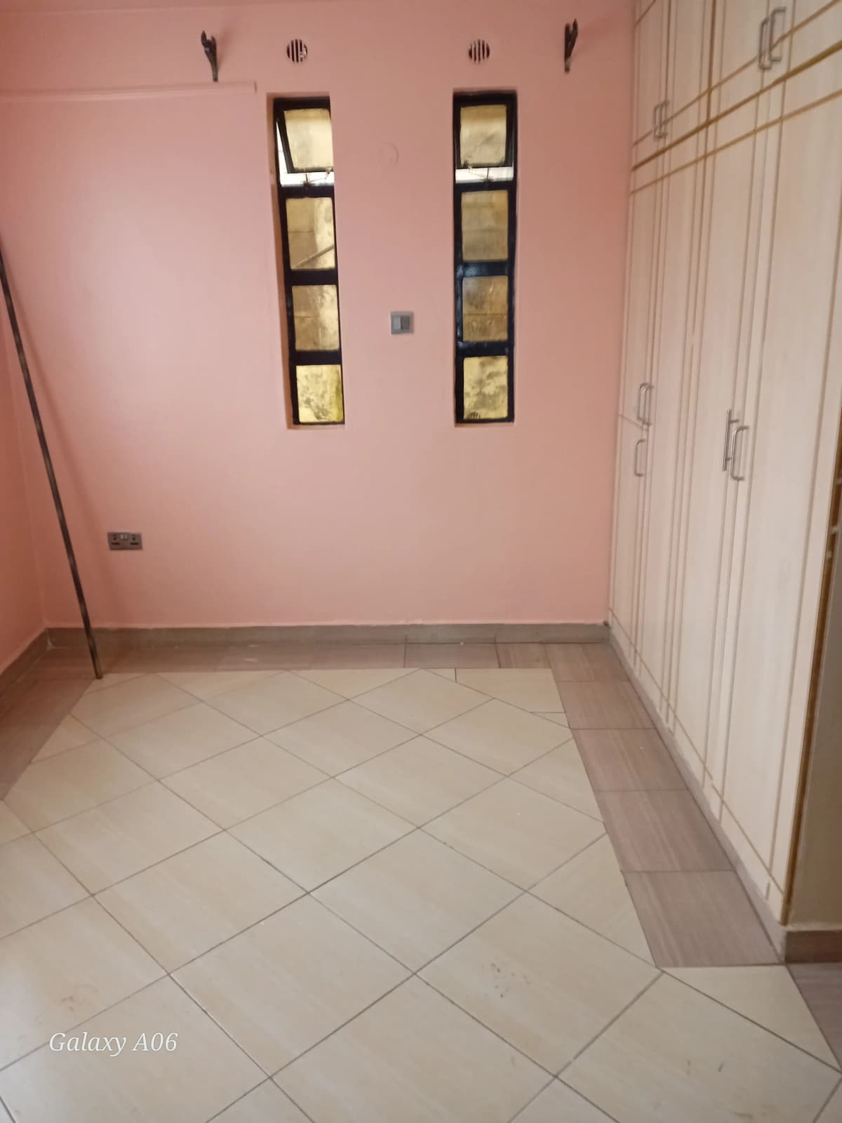 Empty bedroom with pink walls and tiled flooring