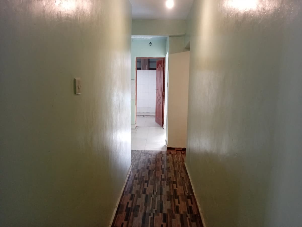 Narrow hallway with wooden flooring and white walls