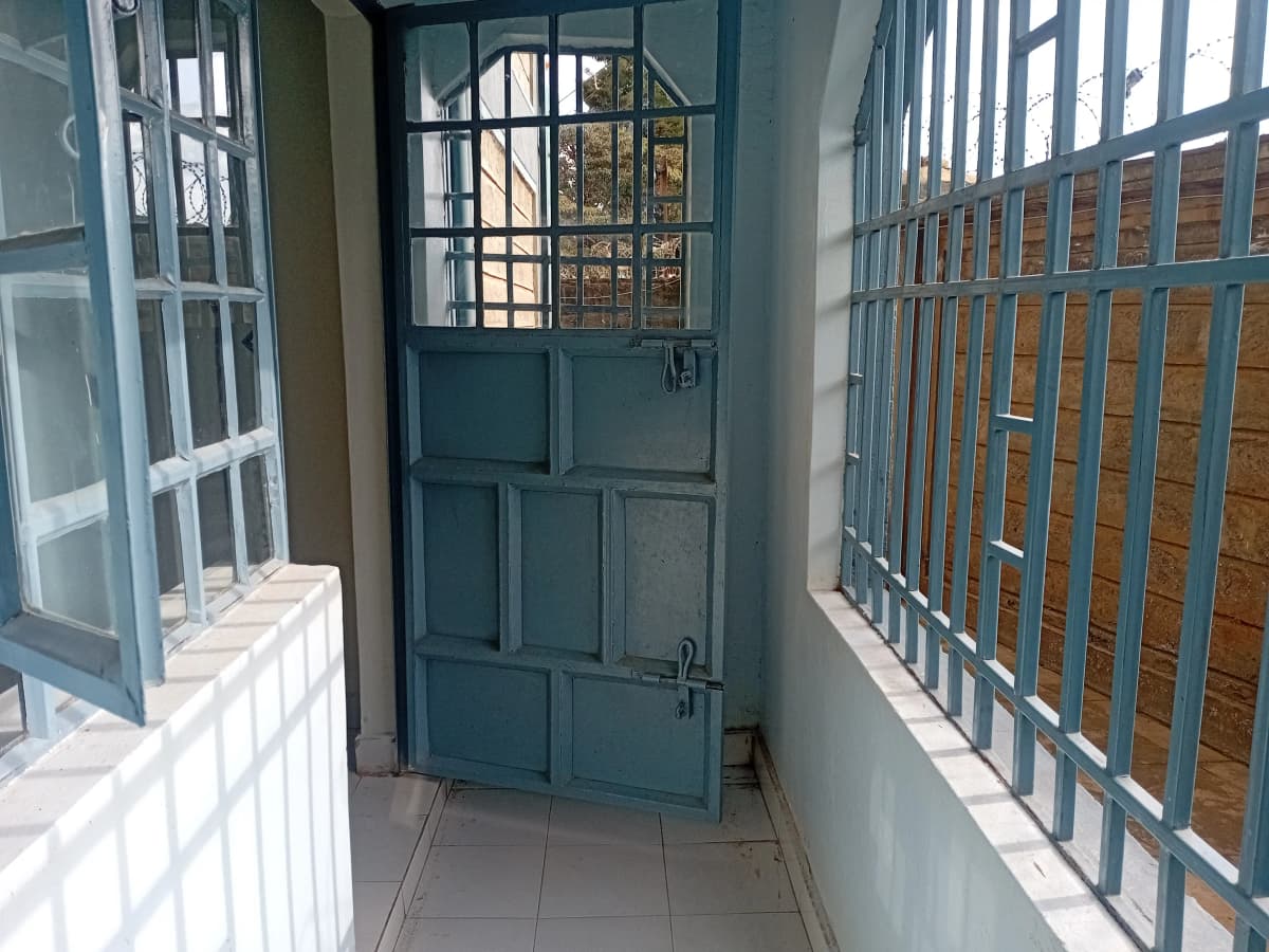 Narrow covered balcony with blue doors and barred windows