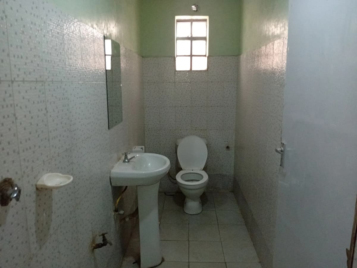 Small bathroom with pedestal sink, toilet, and window
