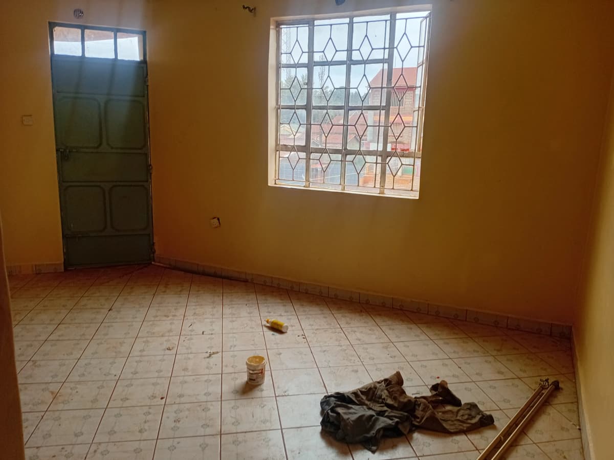 Empty bedroom with tile flooring and barred window