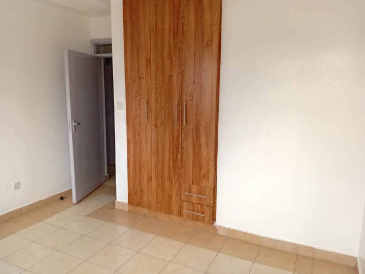 Empty bedroom with wooden wardrobe and tiled floor