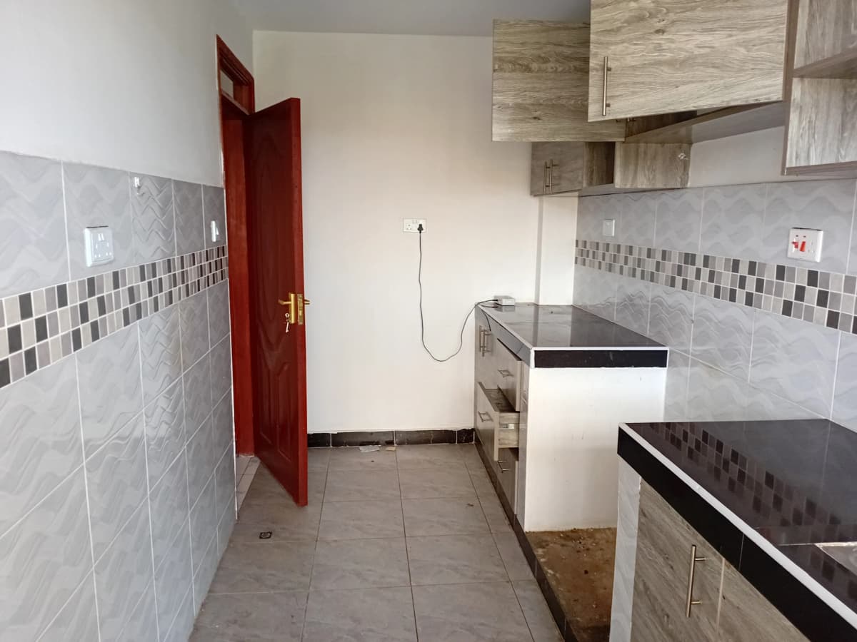 Galley kitchen with tiled walls, basic cabinetry, gas stove