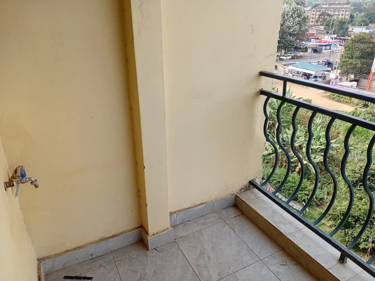 Balcony with metal railing overlooking street and compound