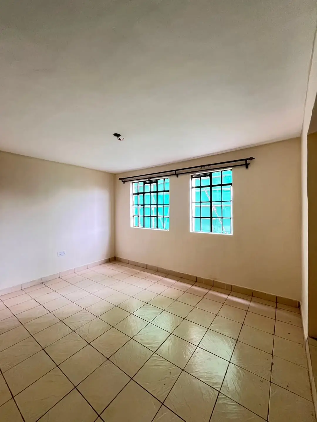 Empty bedroom with tiled floor and barred windows