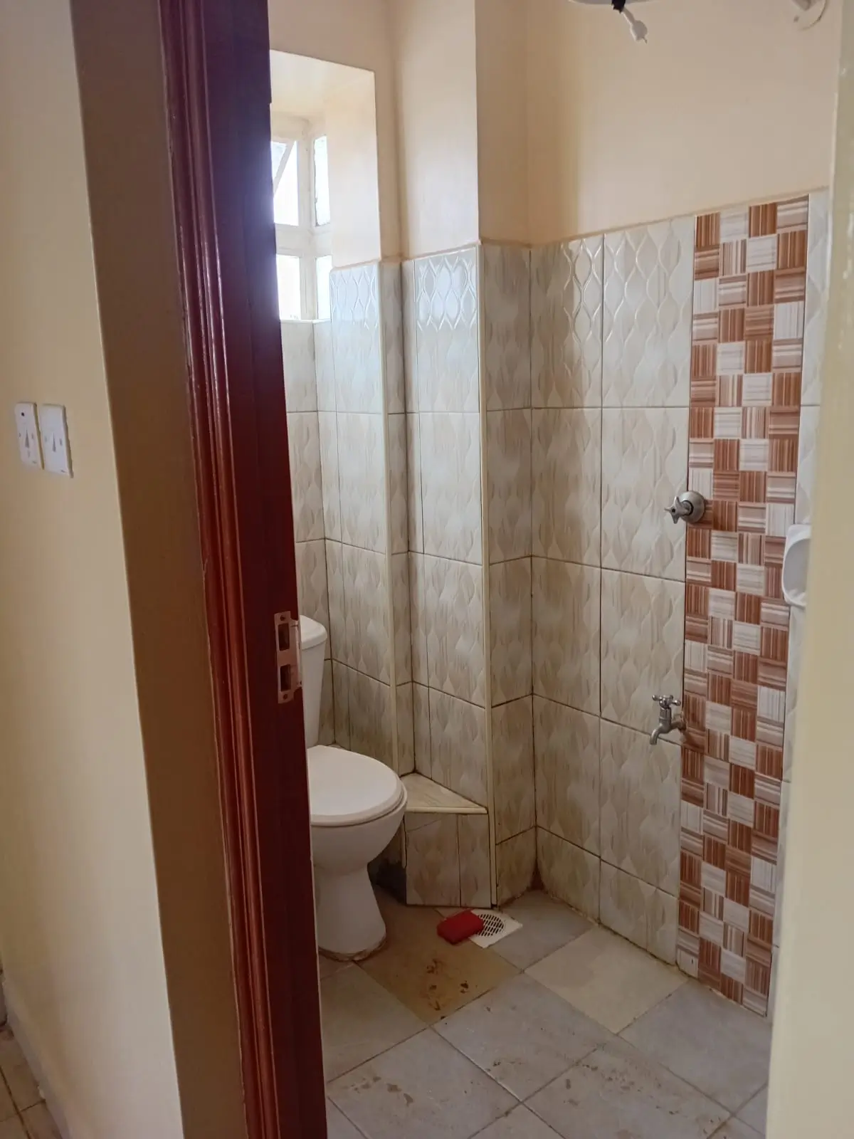 Basic bathroom with toilet, tiled shower area, decorative tilework