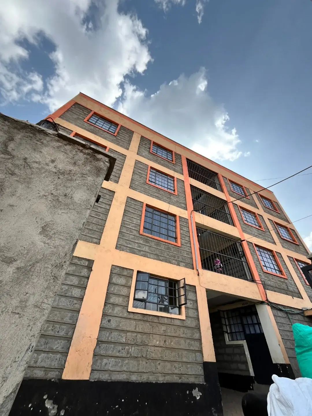 Modern multi-story residential building facade with orange and concrete finish