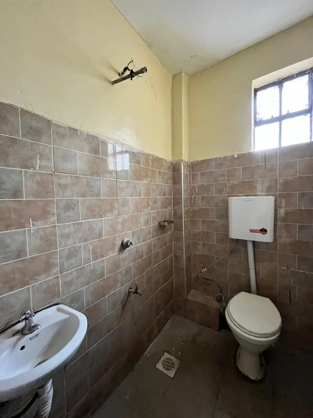 Basic bathroom with wall-mounted sink, toilet, and tiled walls