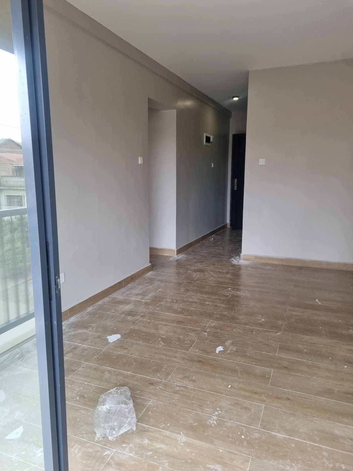 Open-plan living space with wood-effect flooring and balcony access