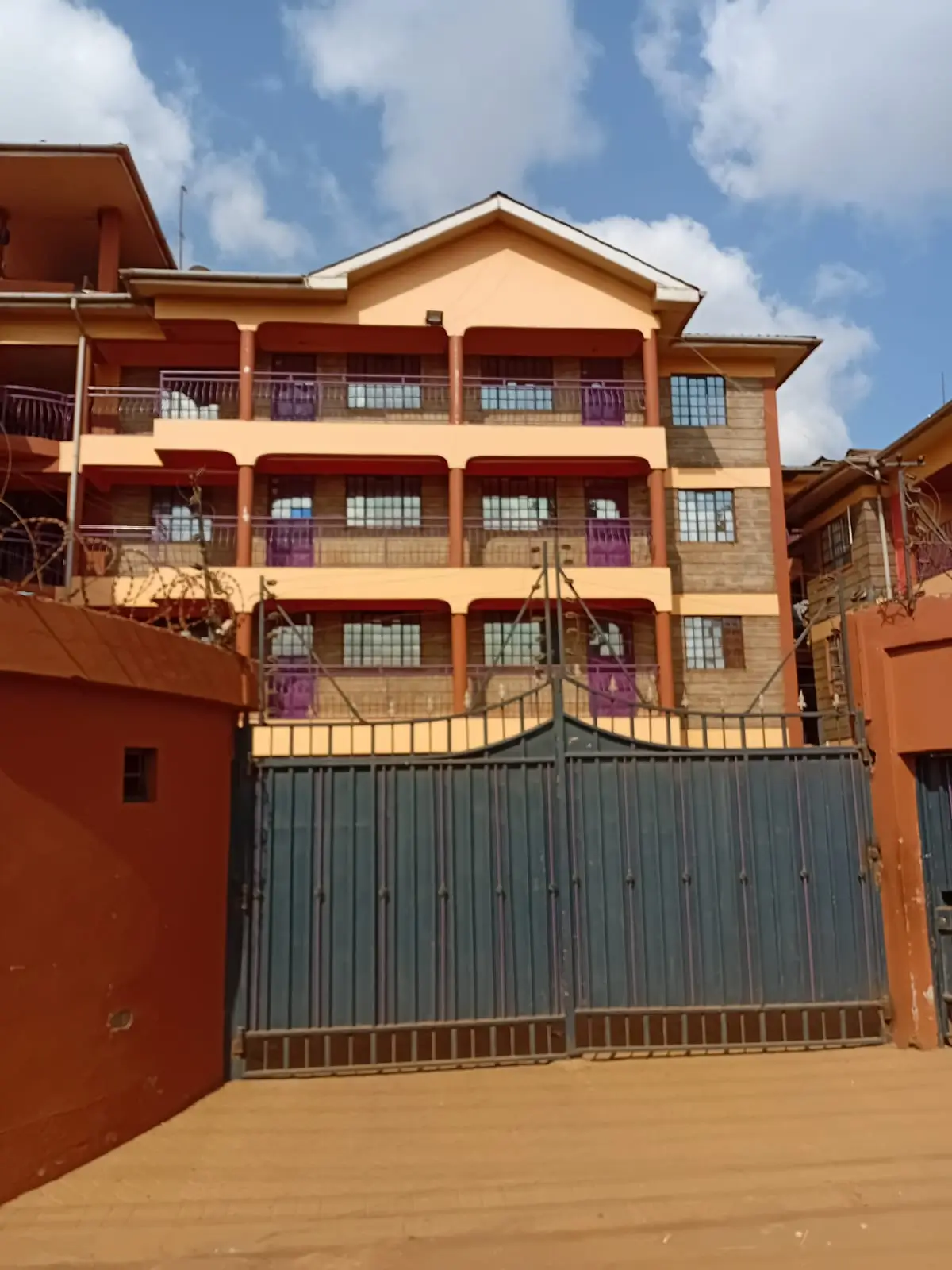 Multi-story residential building with orange facade and gated entrance