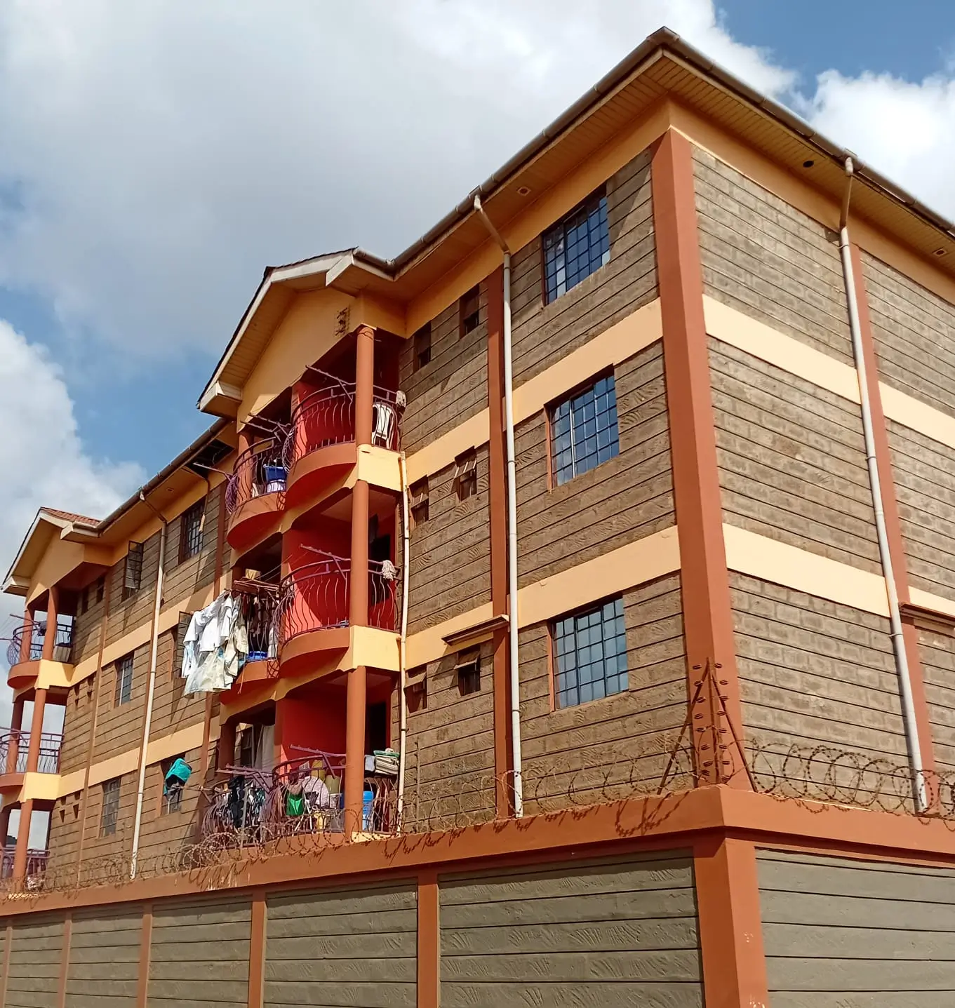 Multi-story residential building with stone facade and red balconies
