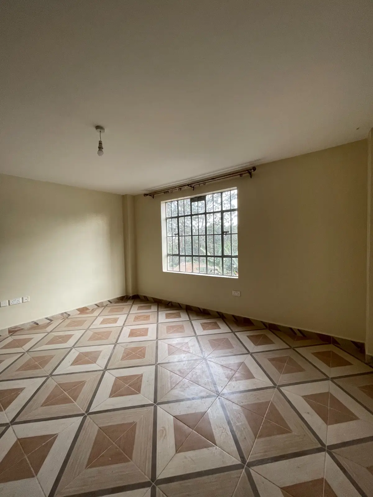 Empty bedroom with geometric tile flooring and barred window