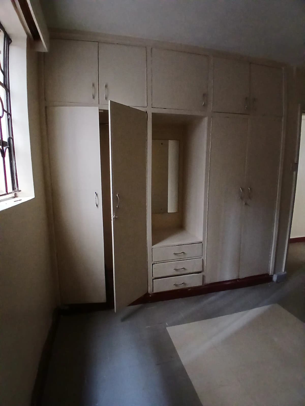 Spacious bedroom with built-in white wardrobes and natural light
