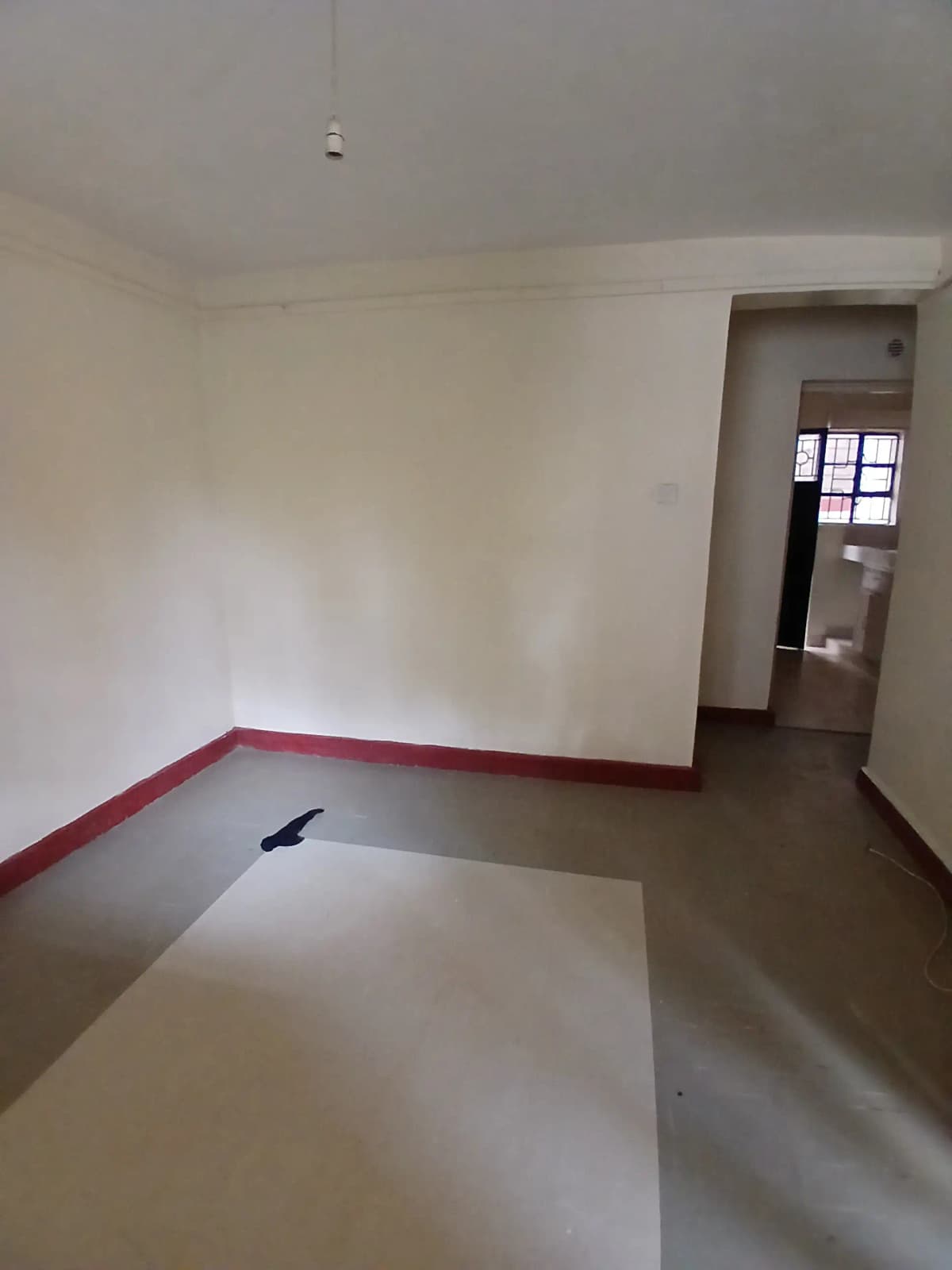 Empty living room with red trim detail and doorway access