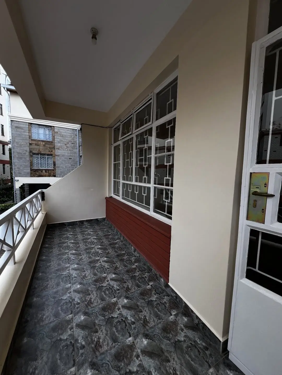 Covered balcony with dark tiled floor and white railings