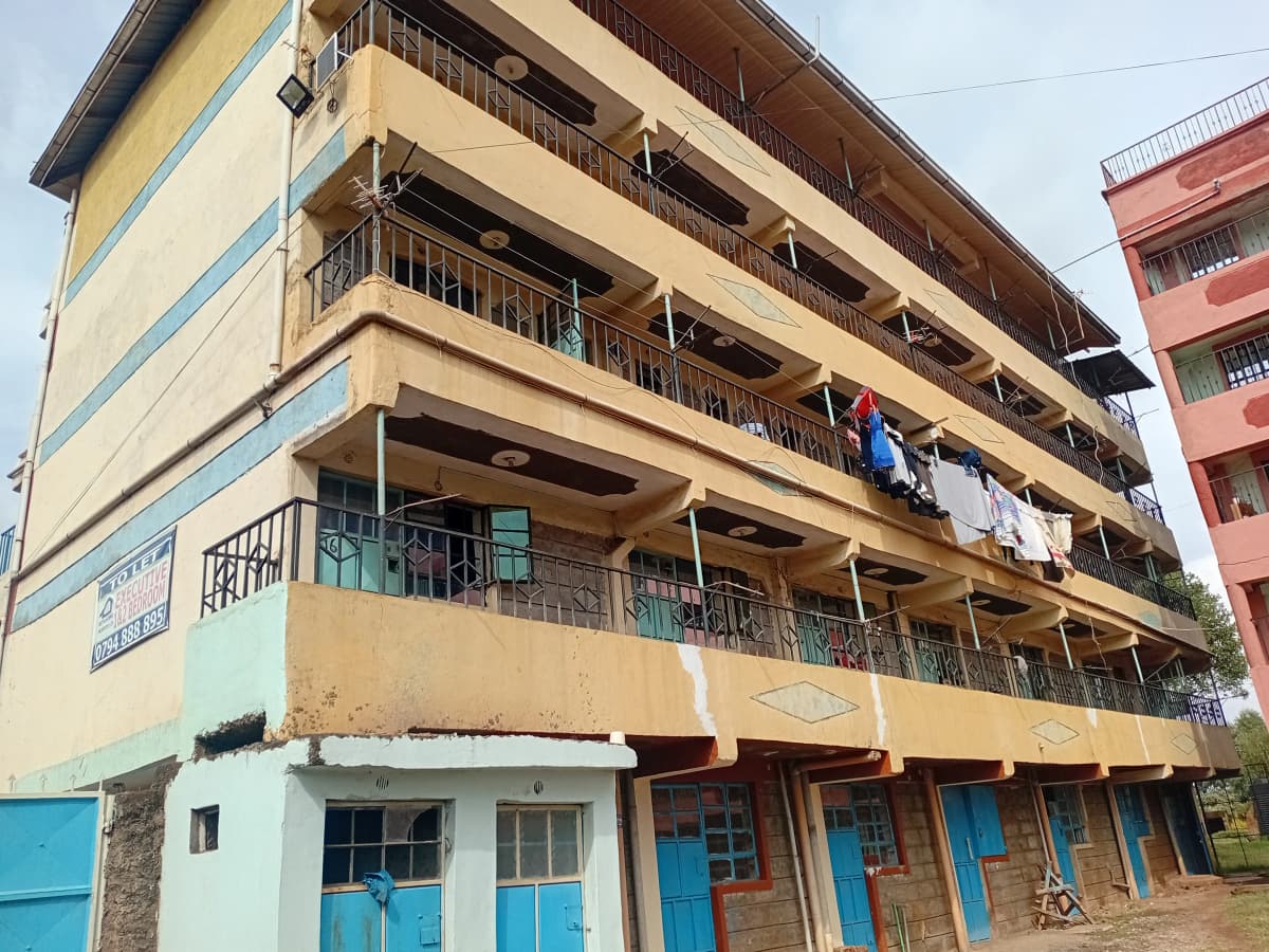 Multi-story residential building facade with balconies and ground-floor shops