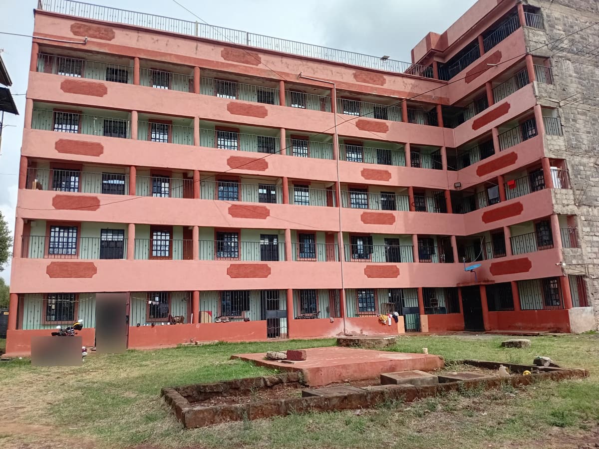 Multi-story residential building with coral-red facade and balconies