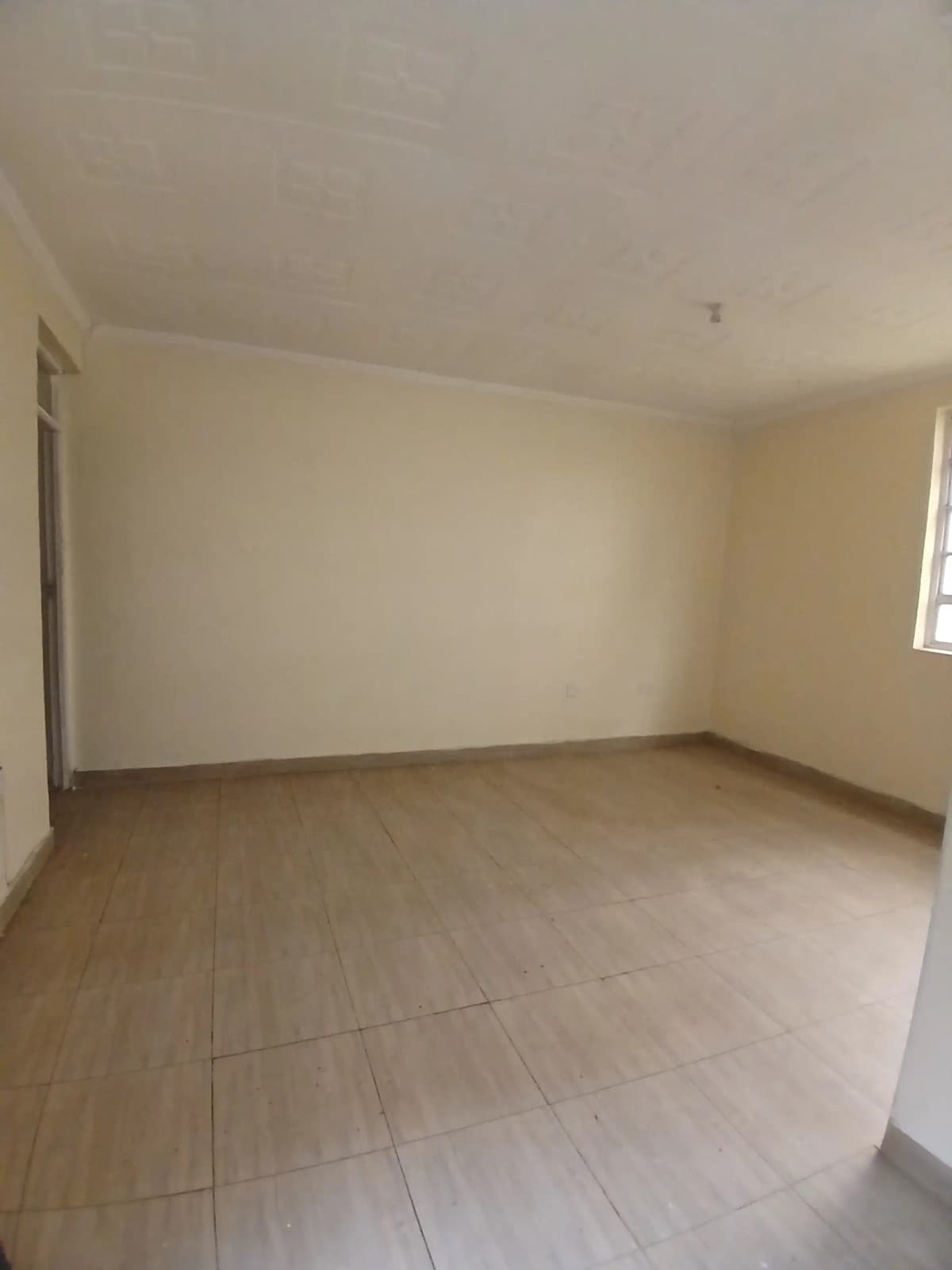 Empty living room with beige walls and tiled flooring
