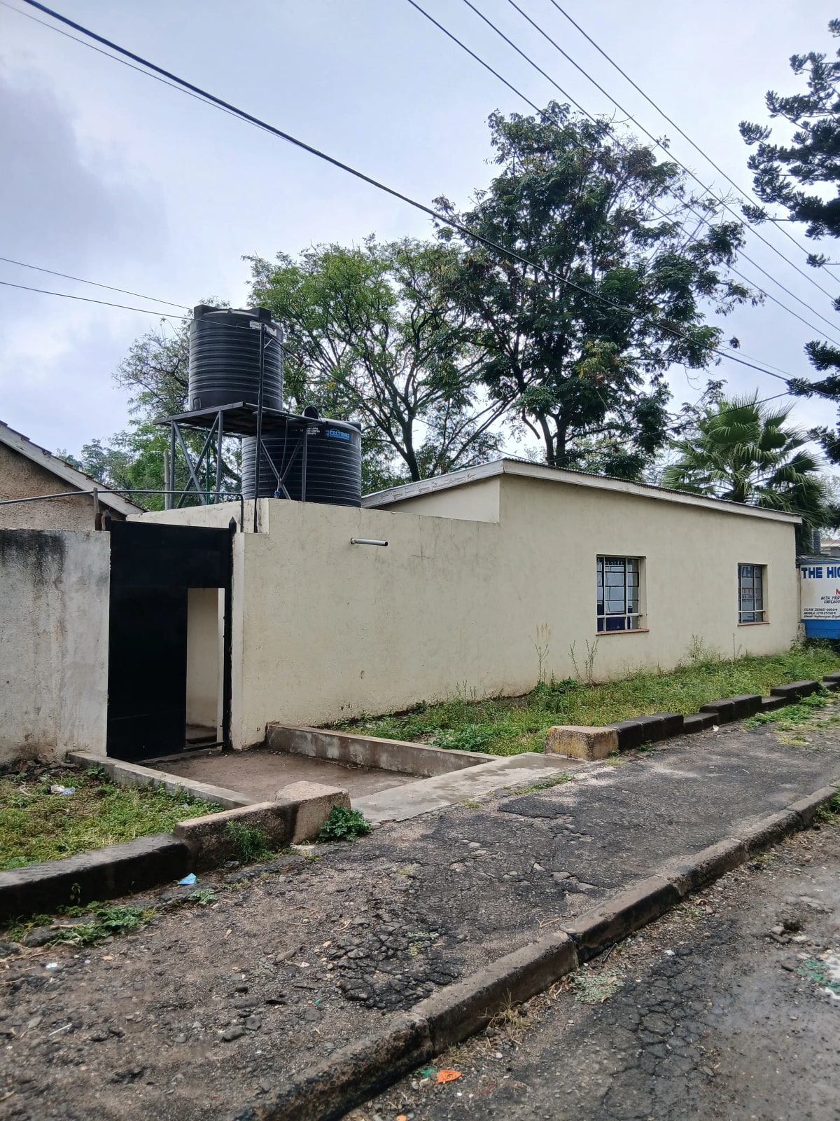 Single-story residential building with cream facade and water tank