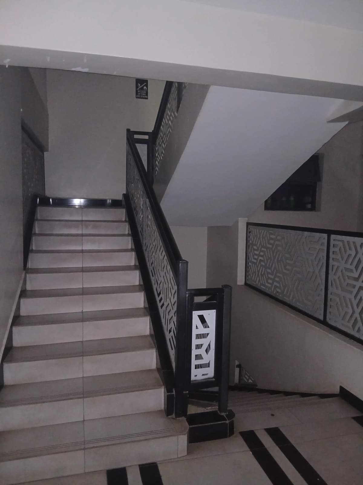 Interior staircase with black metal railings and tiled steps