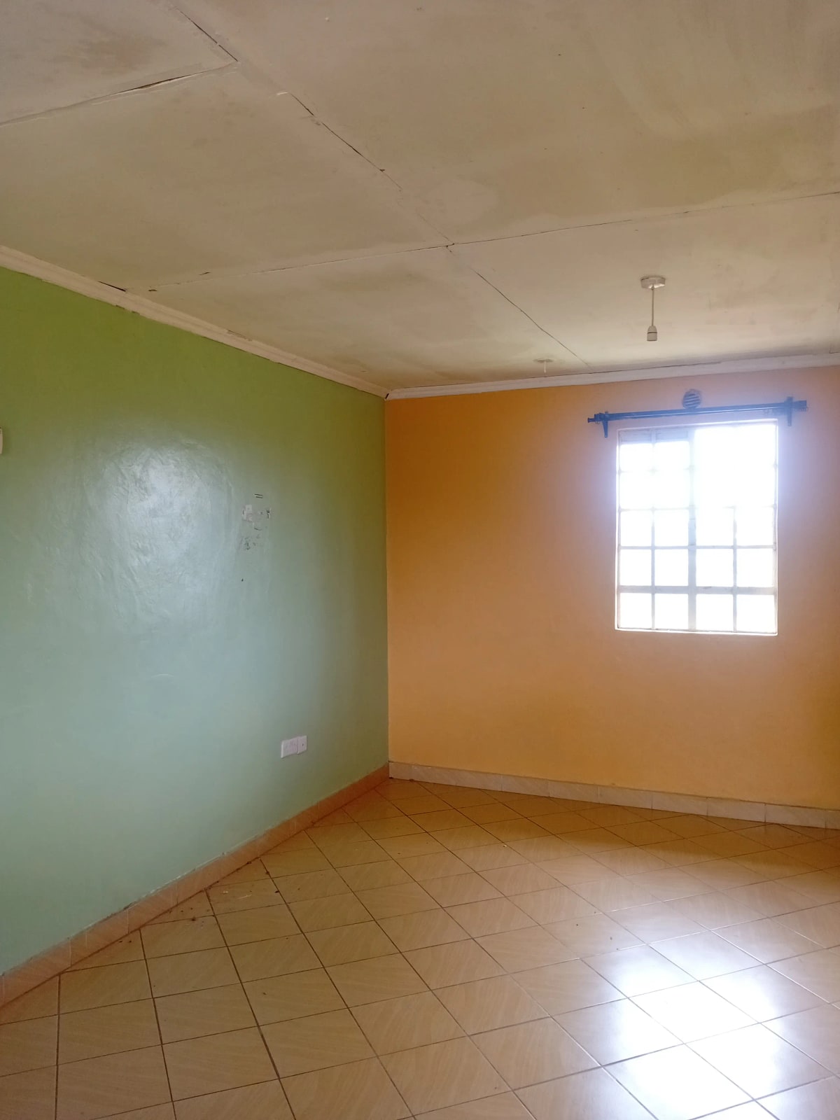 Empty room with terracotta tile floor and colorful walls