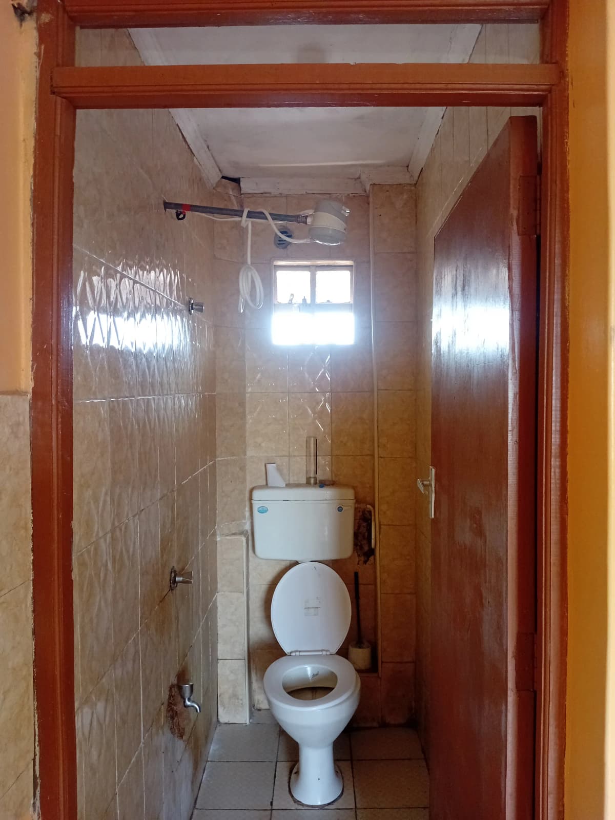 Compact bathroom with toilet, shower enclosure, natural light