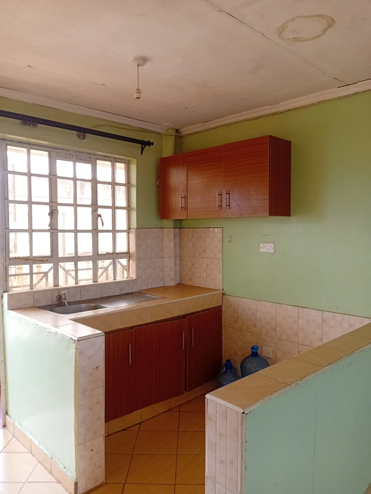 Compact kitchen with red cabinetry and tiled countertops