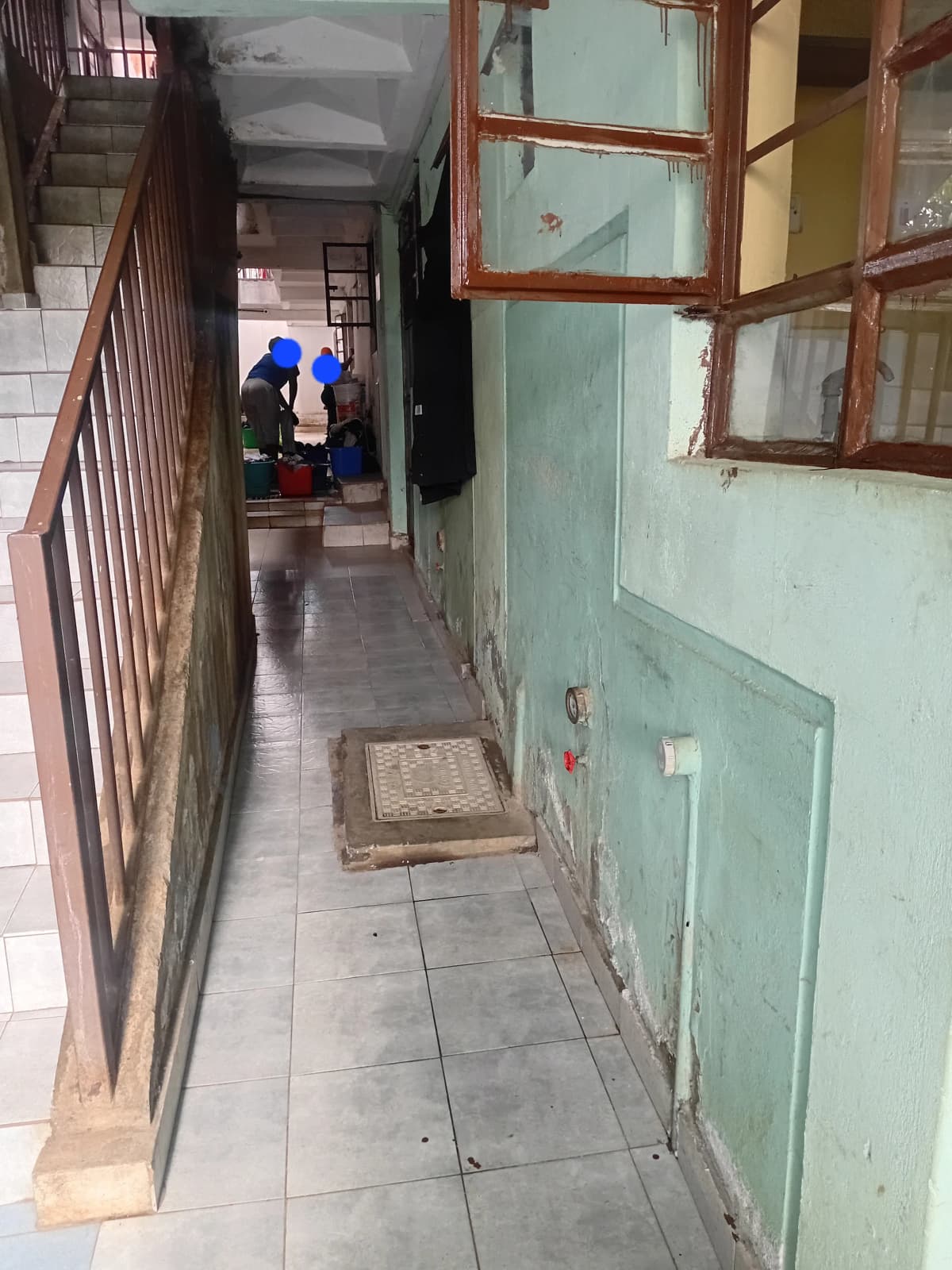 Narrow residential corridor with tiled flooring and metal railing