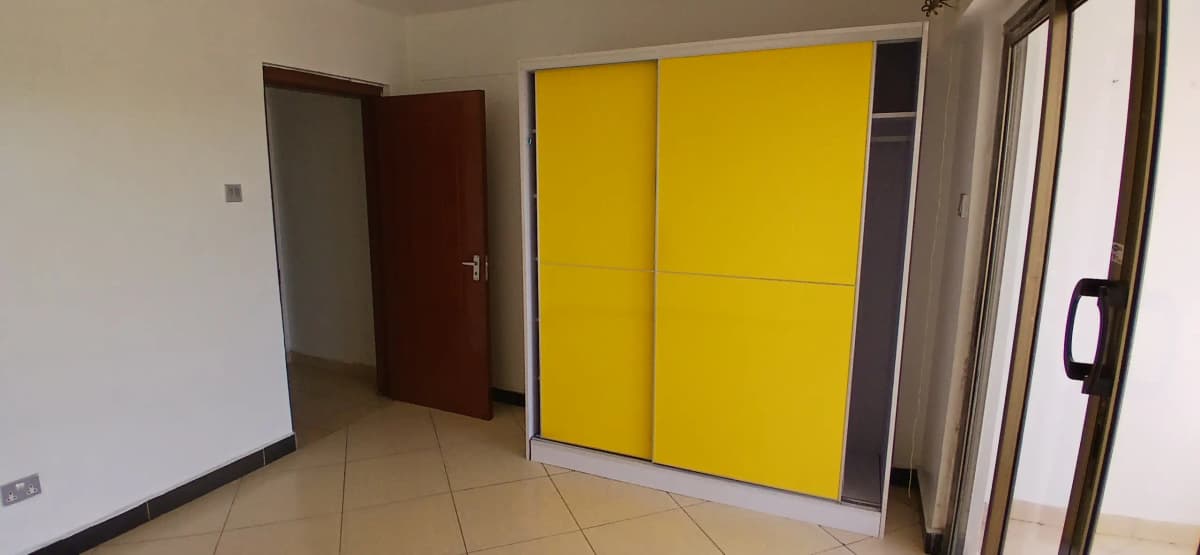 Bedroom with yellow built-in wardrobe and tiled flooring