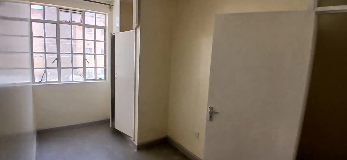 Empty bedroom with window, bare walls, minimal furnishings