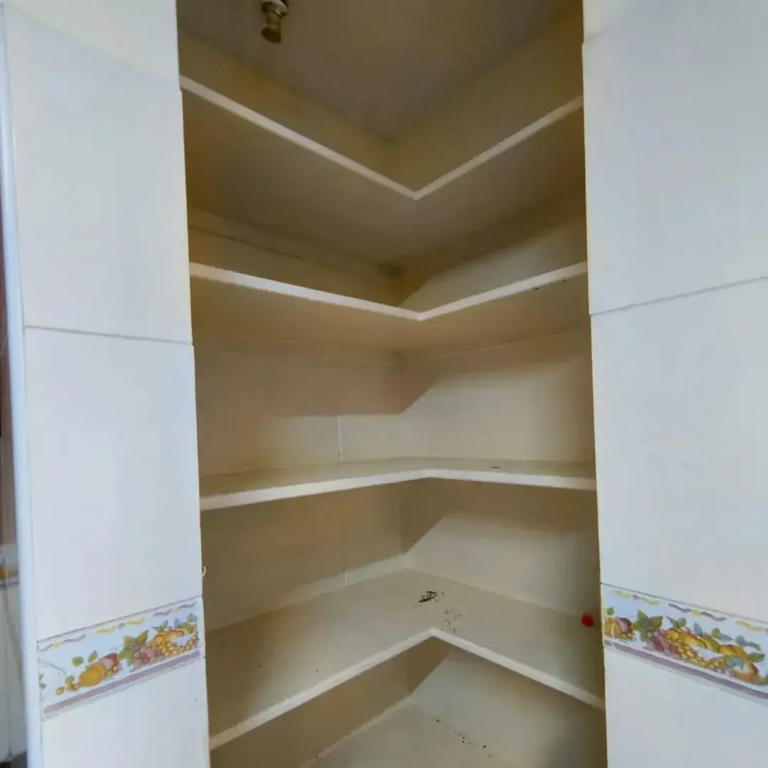 Built-in corner pantry with multiple shelves, white tiling