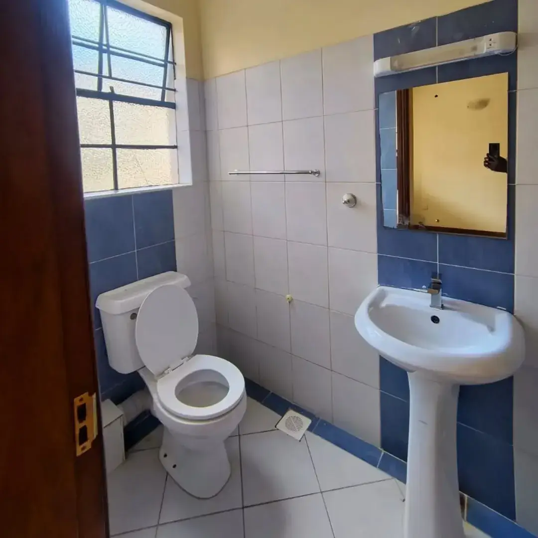 Clean bathroom with pedestal sink, toilet, and tiled walls
