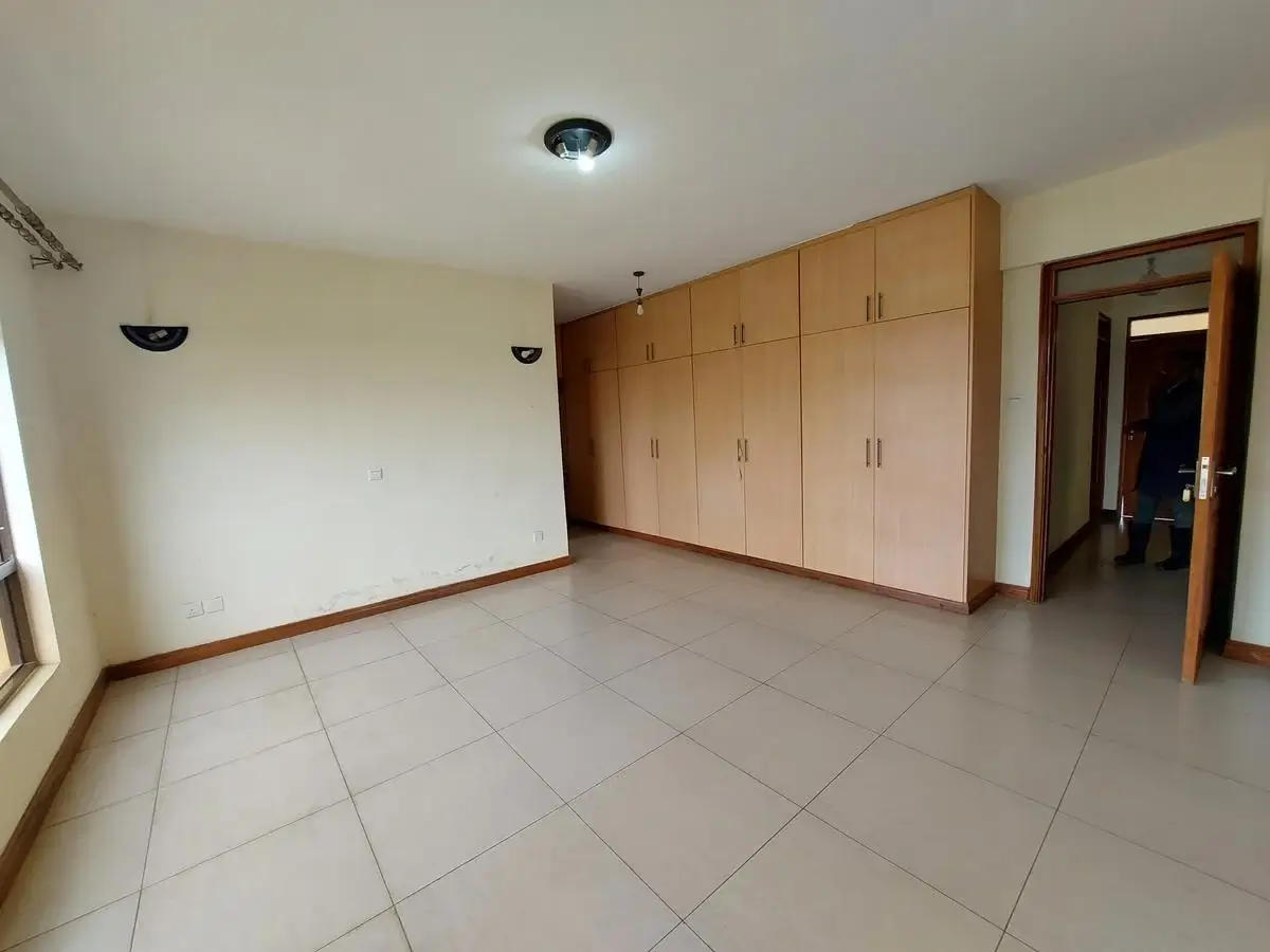 Spacious bedroom with built-in wooden wardrobes and tiled floor