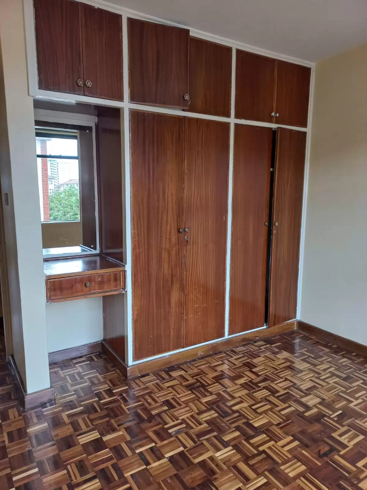 Spacious bedroom with built-in wooden wardrobes and parquet flooring