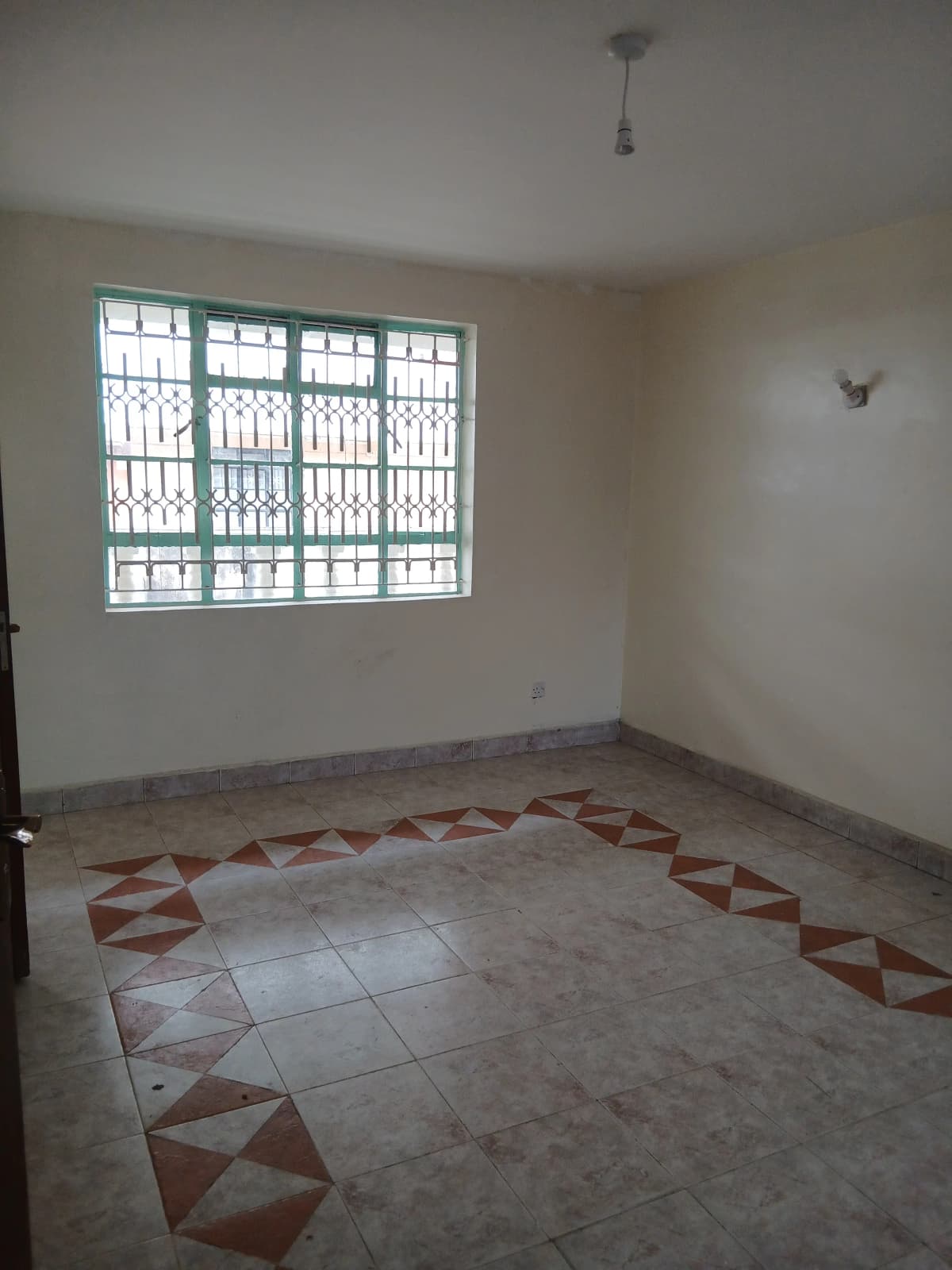 Spacious room with geometric tile floor and barred windows