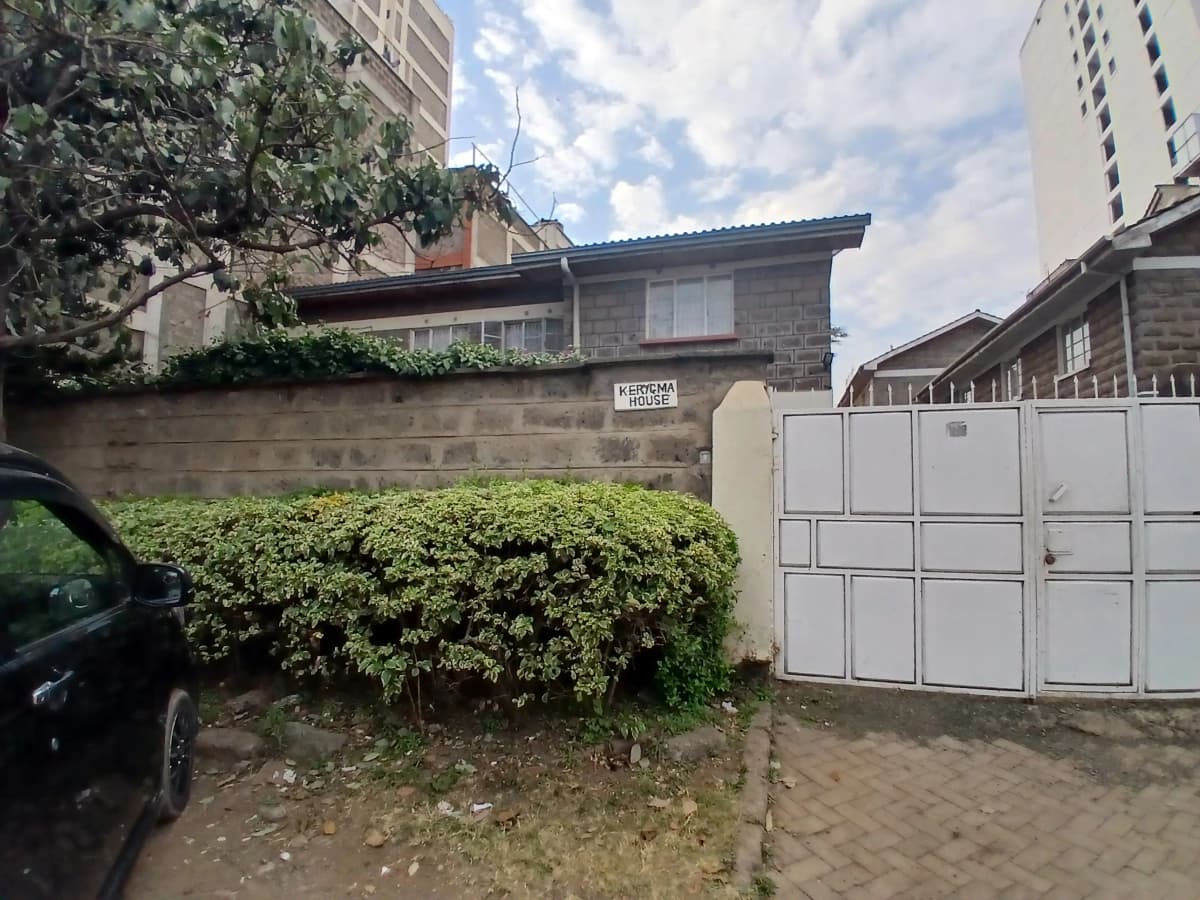 Compound entrance with white metal gates and hedge boundary