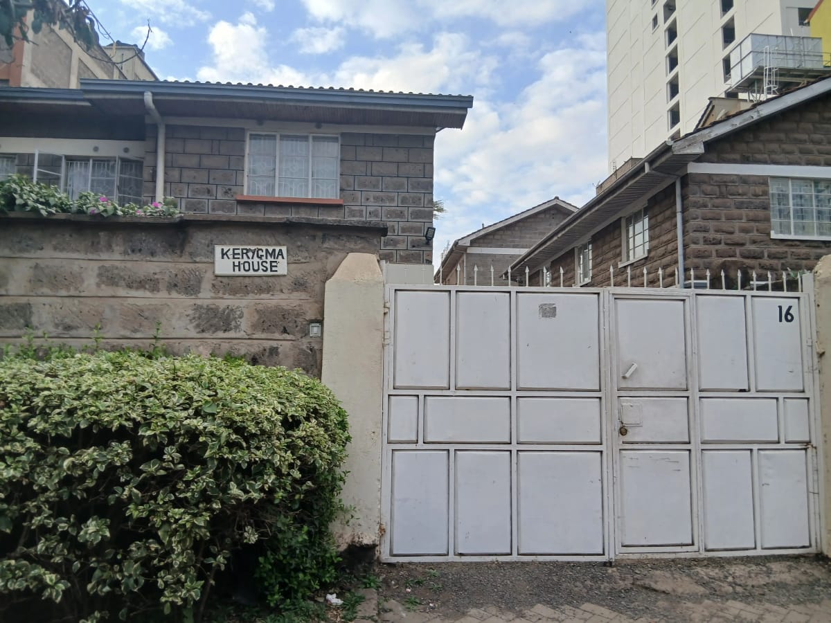 Compound entrance with white metal gate and stone wall