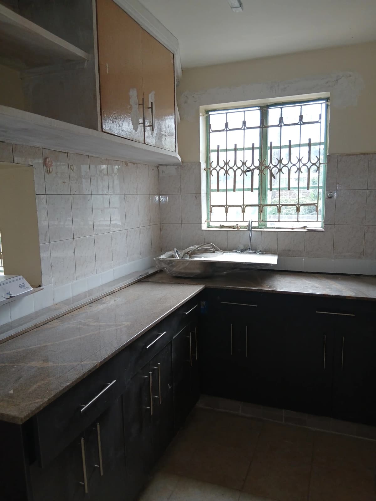 L-shaped kitchen with black cabinets and white tile backsplash
