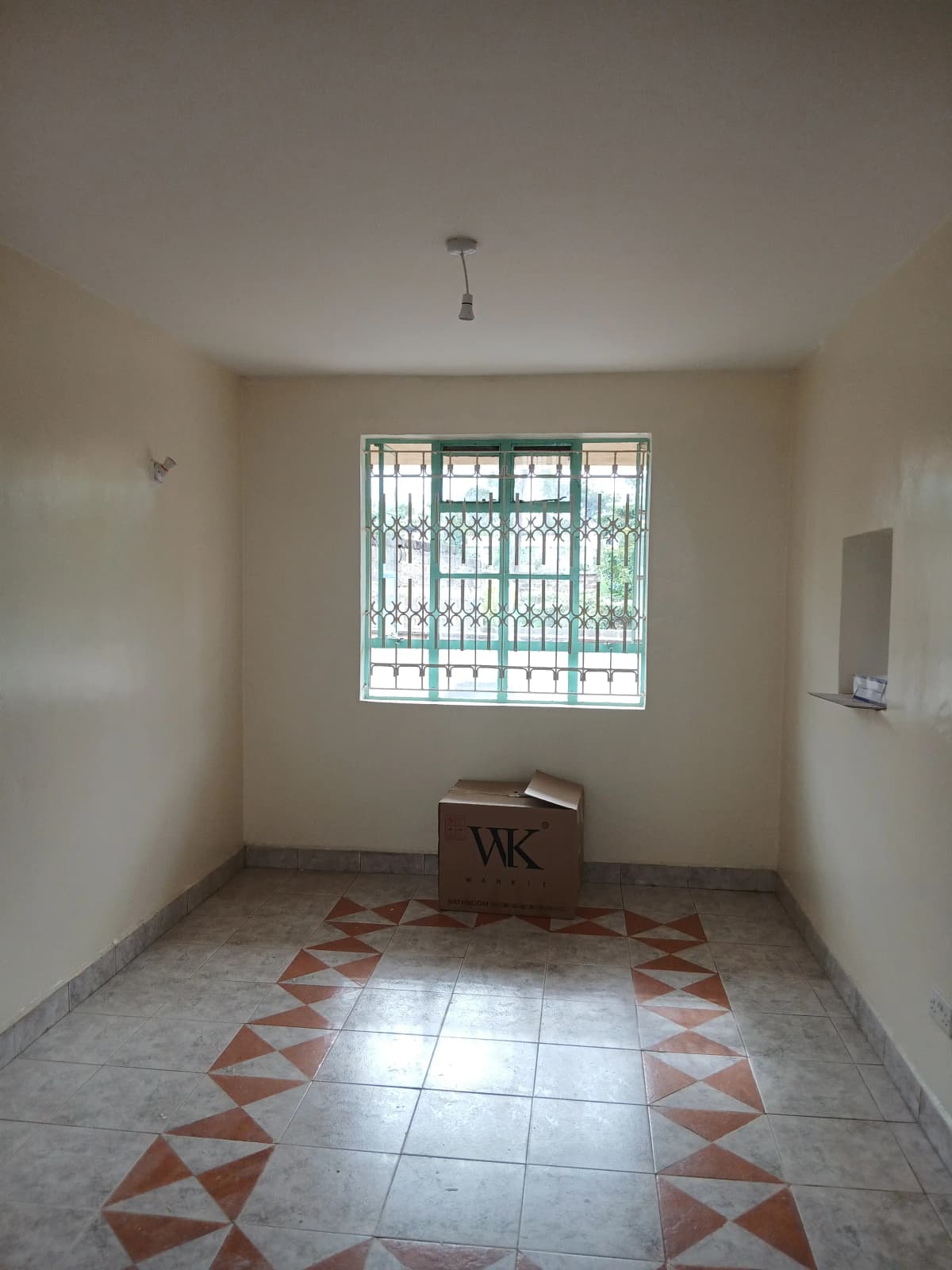 Empty room with geometric tile floor and barred window