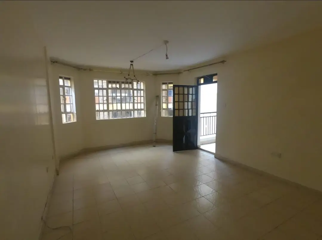Spacious empty living room with multiple windows and balcony access