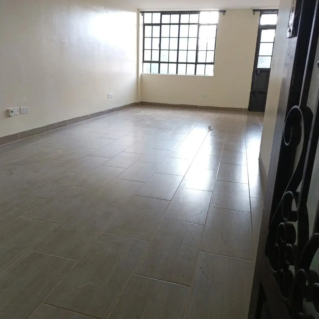 Spacious empty living room with tiled flooring and natural light