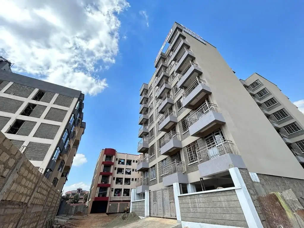 Modern multi-story residential building with balconies and compound gate