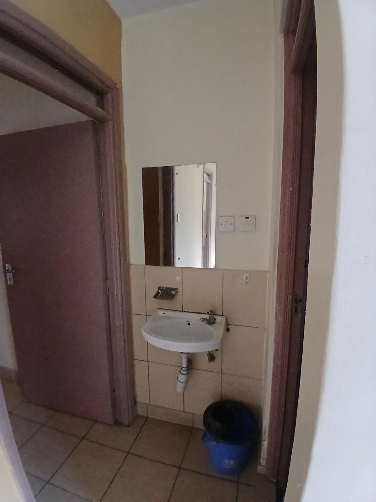 Compact bathroom with wall-mounted sink and mirror