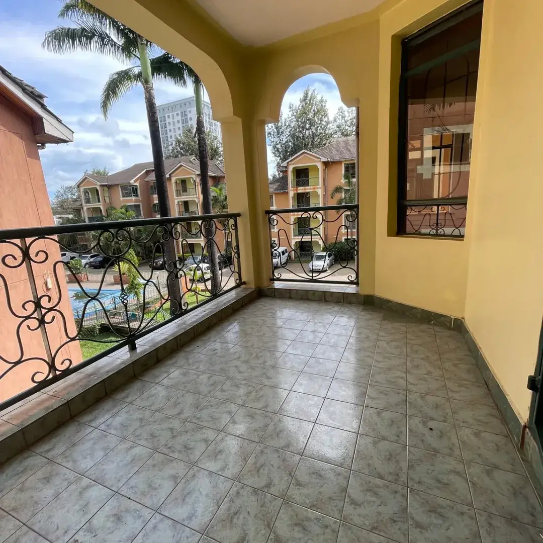 Spacious balcony with tiled floor and ornate railing overlooking compound