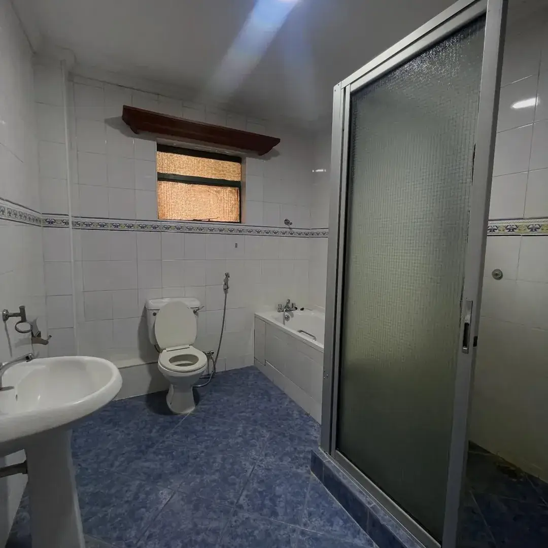 Bathroom with toilet, sink, and enclosed shower cubicle